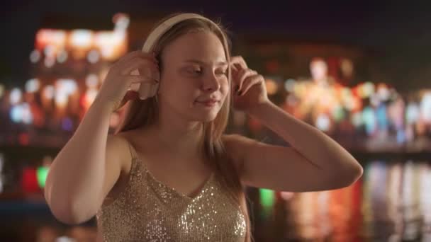 Молодая Женщина Слушает Музыку Больших Белых Наушниках Фоне Размытого Городского — стоковое видео
