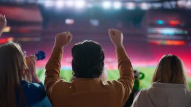 Bir spor sahasında siluet futbol fanatiklerinin heyecan verici bir fotoğrafı, kollarını havaya kaldırıp kutlama yapıyorlar, stadyumdaki aksiyondan büyüleniyorlar, o anın tutkusuna kapılıyorlar..
