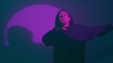 İç ritmini hip hop dansı ile kanalize eden bir kız, renkli spot ışıklarının ışıl ışıl renkleriyle aydınlatılıyor. Her dinamik ve cesur adımın kentsel ifadenin canlı ritmini yansıtmasını izleyin.