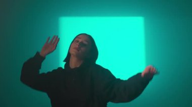 Bir kız dansçı hip hop yapıyor. Solo performans, müzik ve hareket arasındaki güçlü bağlantıyı vurgulayan göz kamaştırıcı çok renkli ışıkların arka planına göre ayarlanır..