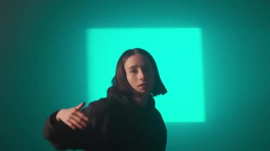 Bir kız dansçı hip hop yapıyor. Solo performans, müzik ve hareket arasındaki güçlü bağlantıyı vurgulayan göz kamaştırıcı çok renkli ışıkların arka planına göre ayarlanır..