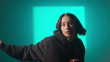 Bir kız dansçı hip hop yapıyor. Solo performans, müzik ve hareket arasındaki güçlü bağlantıyı vurgulayan göz kamaştırıcı çok renkli ışıkların arka planına göre ayarlanır..