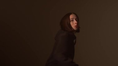 Bir kız dansçı hip hop yapıyor. Solo performans, müzik ve hareket arasındaki güçlü bağlantıyı vurgulayan göz kamaştırıcı çok renkli ışıkların arka planına göre ayarlanır..