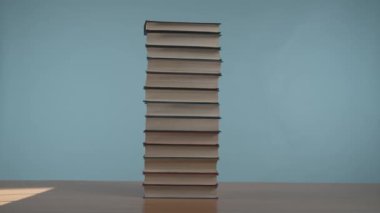 Stop motion video: pencereden gelen ışık, yumuşak mavi arka planda, ahşap bir masa üzerindeki renkli kapaklı eski kitap yığınına çarpar.