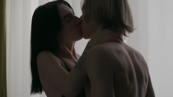 爱亲密关系 一对年轻夫妇在公寓里的肖像 男人和女人赤身裸体地站在窗前 激情和亲密的亲吻 — 图库视频影像
