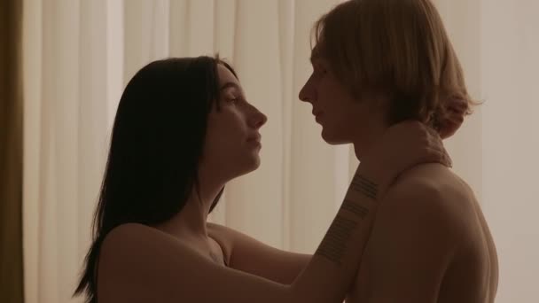 爱亲密关系 一对年轻夫妇在公寓里的肖像 男人和女人赤身裸体地站在窗前 激情和亲密的亲吻 — 图库视频影像