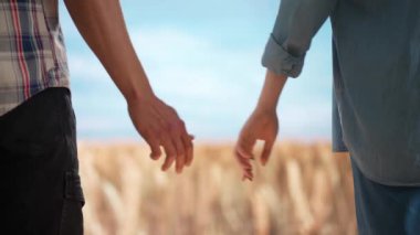Tarım ve modern teknoloji kavramı. Çiftçiler büyük buğday tarlalarına ve mavi gökyüzüne karşı. Erkek ve kadın tarım işçileri tarlada el ele tutuşuyorlar..