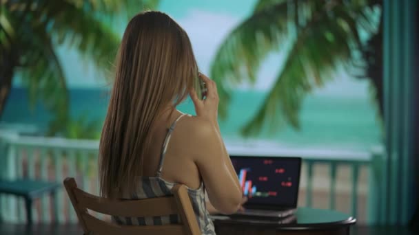 自由职业和自营职业生活方式的概念 从事远距离工作和旅行的女性 在热带海滩度假胜地的笔记本电脑上工作的年轻女自由撰稿人 用智能手机聊天 向后射击 — 图库视频影像