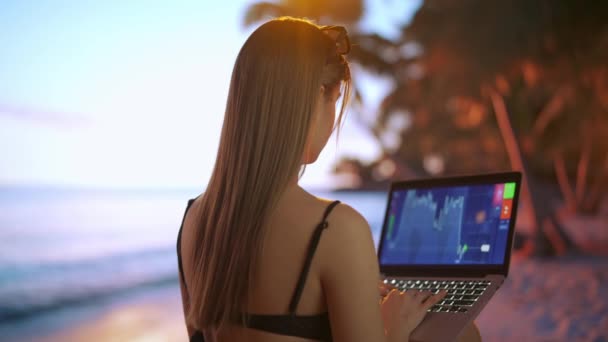 自由职业和自营职业生活方式的概念 从事远距离工作和旅行的女性 年轻的自由撰稿人在日落时分坐在热带海滩上 手握笔记本电脑 工作着 — 图库视频影像