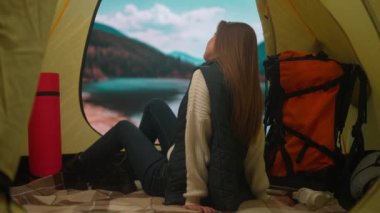 Kamp ve macera konsepti. Kamp alanında gezen, yürüyüş yapan, doğayı keşfeden biri. Genç bir kadın göl kıyısındaki çadırda oturuyor. Dağlarda, tatilde ve dışarıda..