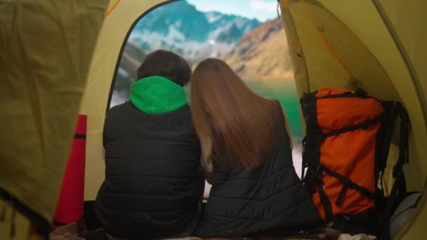 キャンプと冒険のコンセプト キャンプ場の人々は 自然を探索し 旅行し ハイキングします 若い愛するカップルは 山の湖岸のテントの中に座って 休日と休暇を屋外で — ストック動画