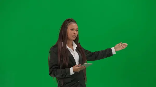 テレビニュースレポートライブ放送広告コンセプト クロマキーの緑色の背景で隔離された女性の記者は アフリカ系アメリカ人女性のニュースホストがタブレットで話すショーは空の領域を示しています — ストック写真