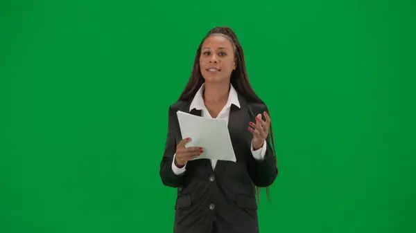 电视新闻报道和现场直播广告的概念 女性记者在彩色键绿色屏幕背景上被隔离 身穿西装的非洲裔美国女主持人阅读纸质文件和谈话 — 图库照片