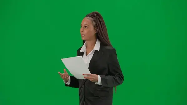 电视新闻报道和现场直播广告的概念 女性记者在彩色键绿色屏幕背景上被隔离 身穿西装的非洲裔美国女主持人阅读纸质文件和谈话 — 图库照片