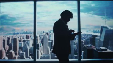 Şirket reklam konsepti. Ofiste başarılı bir iş adamı. Man ceo hedge fonu üst yöneticisi tablet tutuyor sabah manzaralı pencerenin önünde çalışıyor.