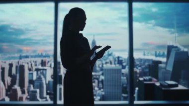 Şirket reklam konsepti. Ofiste başarılı bir iş kadını. Kadın ceo hedge fonu üst yöneticisi tablet tutuyor sabah manzaralı pencerenin önünde çalışıyor.