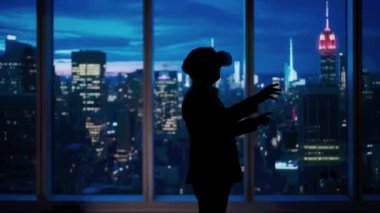 Şirket reklam konsepti. Ofiste başarılı bir iş adamı. VR gözlüklü yatırım fonu yöneticisi akşam manzaralı pencerenin önünde video oyunu oynuyor..