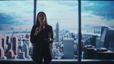 Şirket reklam konsepti. Ofiste başarılı bir iş kadını. Kadın yatırım fonu yöneticisi pencerenin önündeki fincandan kahve içiyor. Şehir manzaralı..