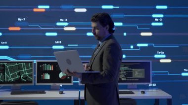 Proje yöneticisi bilgisayar bilimi konsepti. Kontrol odasında teknik destek. Güvenlik ofisinde dizüstü bilgisayarda uzman bir adam. Büyük dijital ekran altyapısı bilgi ağı verilerini izliyor..