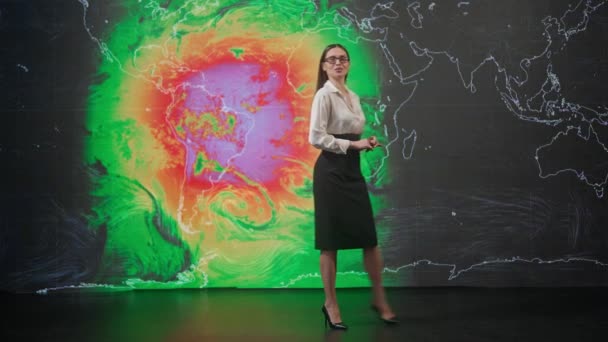 ライブテレビニュース放送コンセプト スタジオの女性プレゼンター 女性アンカーニュースホスト天気予報を提示し 背面に空気 仮想気候地図のグラフィック背景を報告 — ストック動画