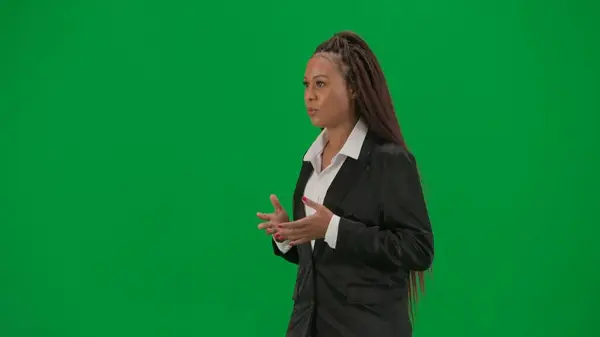 Tv news report and live broadcasting advertisement concept. Female reporter isolated on chroma key green screen background. African American woman news host presenter in suit walking and talking. Half
