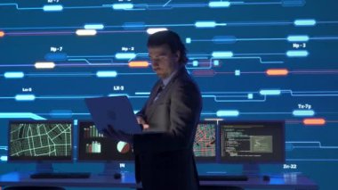 Proje yöneticisi bilgisayar bilimi konsepti. Kontrol odasında teknik destek. Güvenlik ofisinde dizüstü bilgisayarda uzman bir adam. Büyük dijital ekran altyapısı bilgi ağı verilerini izliyor..