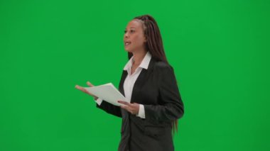 TV haber bülteni ve canlı yayın reklam konsepti. Krom anahtar yeşil ekran arka planında izole edilmiş kadın muhabir. Takım elbiseli Afrikalı Amerikalı kadın haber sunucusu gazete okuyor ve konuşuyor.