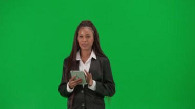 TV haber bülteni canlı yayın reklam konsepti. Krom anahtar yeşil ekran arka planında izole edilmiş kadın muhabir. Afro-Amerikalı kadın haber sunucusu, tabletle konuşuyor..