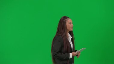 TV haber bülteni canlı yayın reklam konsepti. Krom anahtar yeşil ekran arka planında izole edilmiş kadın muhabir. Afro-Amerikalı kadın haber sunucusu, tabletle konuşuyor..