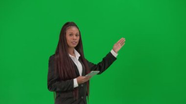 TV haber bülteni canlı yayın reklam konsepti. Krom anahtar yeşil ekran arka planında izole edilmiş kadın muhabir. Afro-Amerikalı kadın haber sunucusu, tabletle konuşuyor..