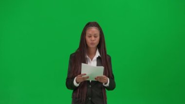TV haber bülteni canlı yayın reklam konsepti. Krom anahtar yeşil ekran arka planında izole edilmiş kadın muhabir. Afrika kökenli Amerikalı kadın haber sunucusu elinde kağıt belgelerle kamerada konuşuyor..