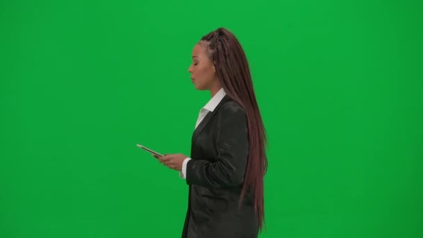 电视新闻报道和现场直播广告的概念 女性记者在彩色键绿色屏幕背景上被隔离 身着西装 拿着石碑的非裔美国女性新闻主持人 — 图库视频影像