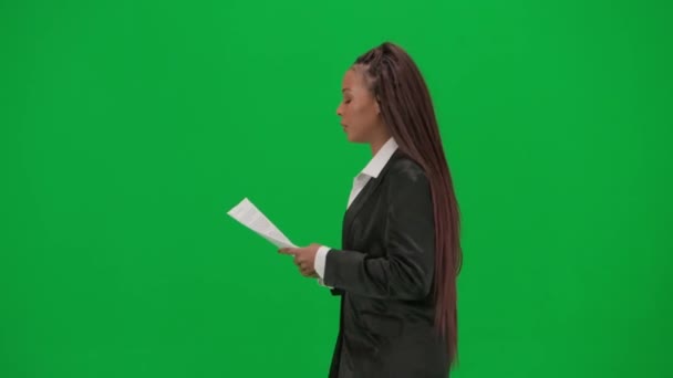 电视新闻报道和现场直播广告的概念 女性记者在彩色键绿色屏幕背景上被隔离 身穿西装的非洲裔美国女主持人阅读纸质文件和谈话 — 图库视频影像