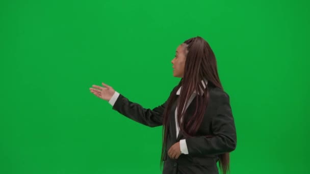 电视新闻报道和现场直播广告的概念 女性记者在彩色键绿色屏幕背景上被隔离 穿着西装的非洲裔美国女新闻主持人指着空旷的空间讲话 — 图库视频影像