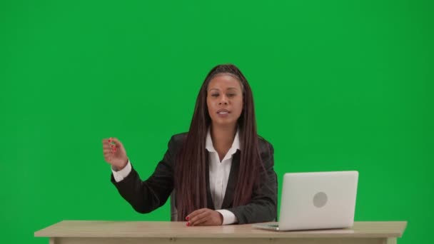 テレビニュースレポートとライブ放送広告コンセプト クロマキーの緑色の背景で隔離された女性の記者は アフリカ系アメリカ人女性ニュースホストがノートパソコン付きデスクでスーツを着用 — ストック動画