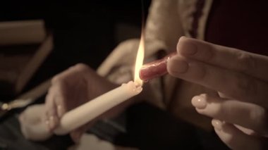 Eski bir harf yaratıcı kavramı. Mumlu, antika kostümlü bir kadın. Rönesans elbiseli kadın elinde balmumu çubuğu tutuyor ve uzun bir mumun aleviyle ısıtıyor. Mektubu mühürlemeye hazırlanıyor..