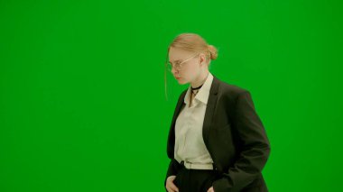 Modern iş kadını yaratıcı reklam konsepti. Krom anahtar yeşil ekranda takım elbiseli kadın portresi. Resmi kıyafetli sarışın iş kadını yürüyüş ve dans ediyor, gülümsüyor..