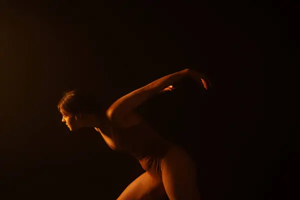 光と影の繊細な相互作用を通したダンスのエッセンスは 白いシフォンで覆われたダンサーが詩とともに動きます 微妙な照明はダンサーの動きの流動性そして優雅さを強調します — ストック写真
