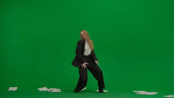 現代のビジネスマンクリエイティブ広告コンセプト クロマキー付きのグリーンスクリーンのビジネスススーツの女性 ブロンドのビジネス女性はチャートで散らばった論文の間で踊ります — ストック写真