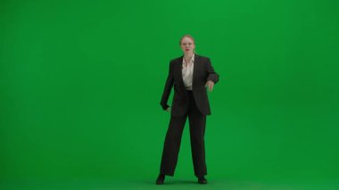 Modern iş kadını yaratıcı reklam konsepti. Krom anahtar yeşil ekranda takım elbiseli kadın portresi. Resmi kıyafetli sarışın iş kadını kameraya şarkı söyleyerek dans ediyor..