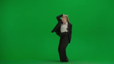 Siyah takım elbiseli kadın yeşil ekranda kromakeyle dans ediyor. Modern iş kadını yaratıcı reklam konsepti.