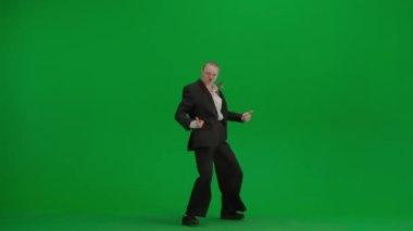 Siyah takım elbiseli kadın yeşil ekranda kromakeyle neşeyle dans ediyor. Modern iş kadını yaratıcı reklam konsepti.