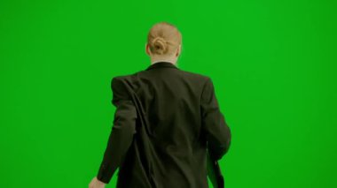 Modern iş kadını yaratıcı reklam konsepti. Krom anahtar yeşil ekranda takım elbiseli kadın portresi. Resmi kıyafetli sarışın bir iş kadını el saatini kontrol ediyor ve koşmaya başlıyor. Geri