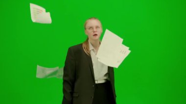 Modern iş kadını yaratıcı reklam konsepti. Krom anahtar yeşil ekranda takım elbiseli kadın portresi. İş kadını kağıt döküman atmaktan bıktı ve dans etmeye başladı..