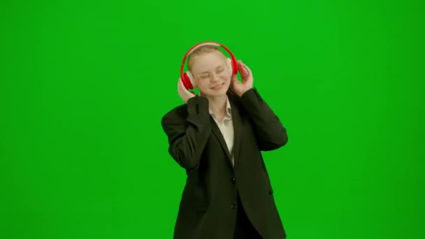 女商人一边用耳机听音乐 一边欢快地跳舞 穿着西服的女人用铬钥匙在绿色屏幕上 现代商务女士创意广告理念 — 图库视频影像