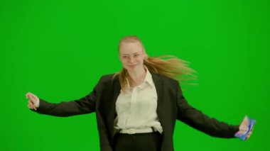 Siyah takım elbiseli kadın yeşil ekranda kromakeyle neşeyle dans ediyor. Modern iş kadını yaratıcı reklam konsepti.