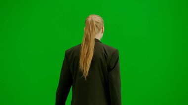Modern iş kadını yaratıcı reklam konsepti. Krom anahtar yeşil ekranda takım elbiseli kadın portresi. Resmi kıyafetli sarışın iş kadını yürüyüş ve dans ediyor, gülümsüyor.