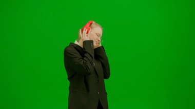 Modern iş kadını yaratıcı reklam konsepti. Krom anahtar yeşil ekranda takım elbiseli kadın portresi. Resmi kıyafetli sarışın iş kadını kulaklıkla yürüyor akıllı telefondan müzik dinliyor.