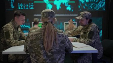 Orduda teknoloji ve iletişim. Bir grup güvenlik ekibi kontrol merkezinde. Askeri karargah gözetim memurları siber polis brifingi, büroda kağıt dökümanlarını kontrol ediyor..
