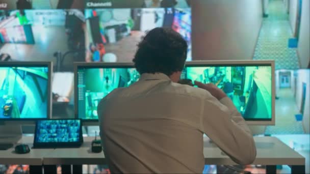 監視とセキュリティのコンセプト 監視センターで働く警備員 監視カメラを見て コーヒーを飲む バックショット コンピュータおよび大きいデジタル スクリーンショーCctvのカメラ映像 — ストック動画